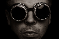 Zwart-wit portret van een man met een unieke lasbril, artistiek en expressief. Deze foto combineert een opvallende stijl met creatief lichtgebruik, ideaal voor kunstprojecten en creatieve portfolios.