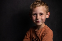 Portret van een 6-jarige met een lief en blij gezicht, tegelijkertijd straalt hij stoerheid uit. Een hartverwarmende en vrolijke uitdrukking vermengd met stoere charme, ideaal voor het vastleggen van onschuldige vreugde en de stoere kant van de jeugd.